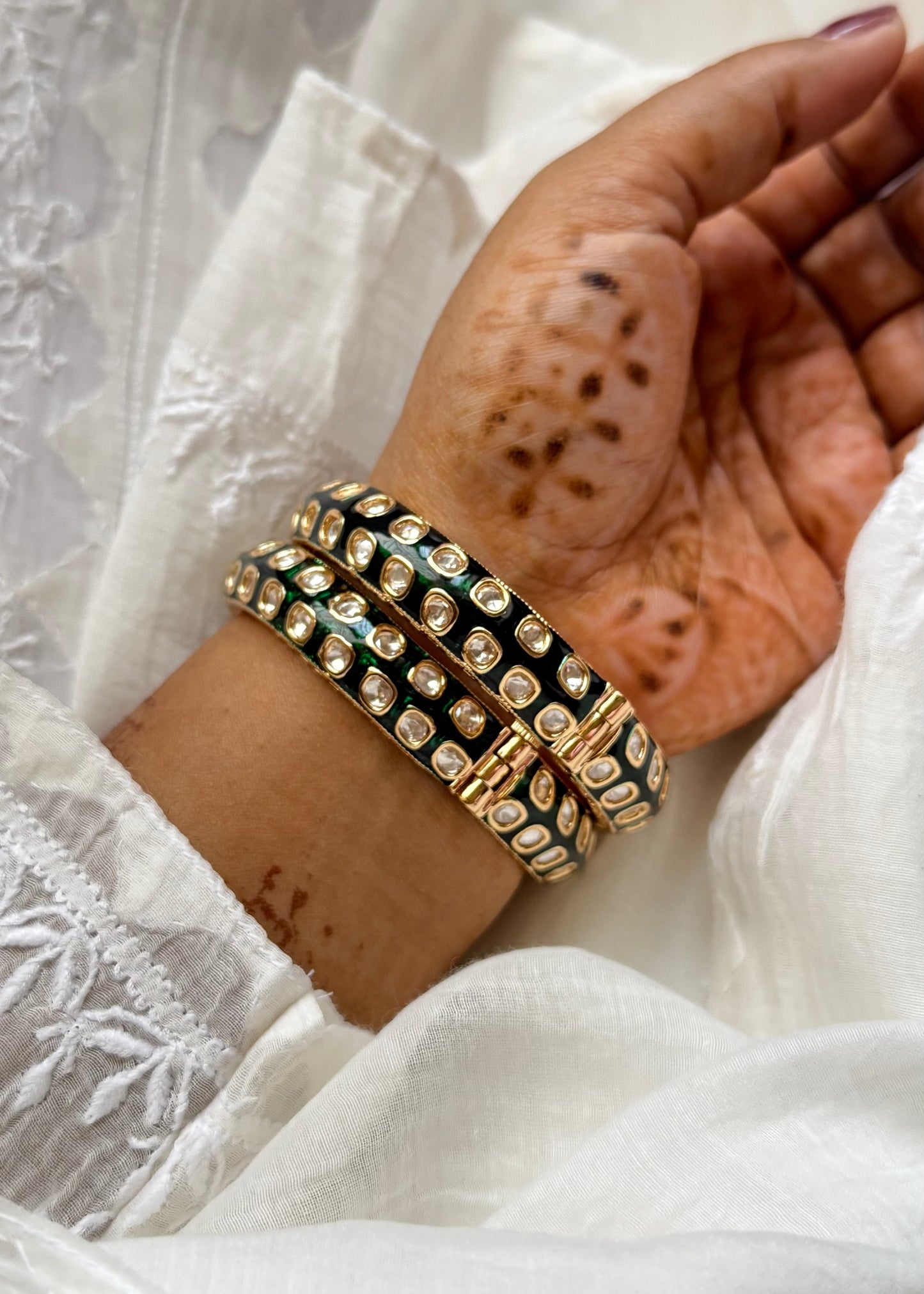 Hand wearing a stack of GREEN MEENAKARI POLKI STUDDED KADAS