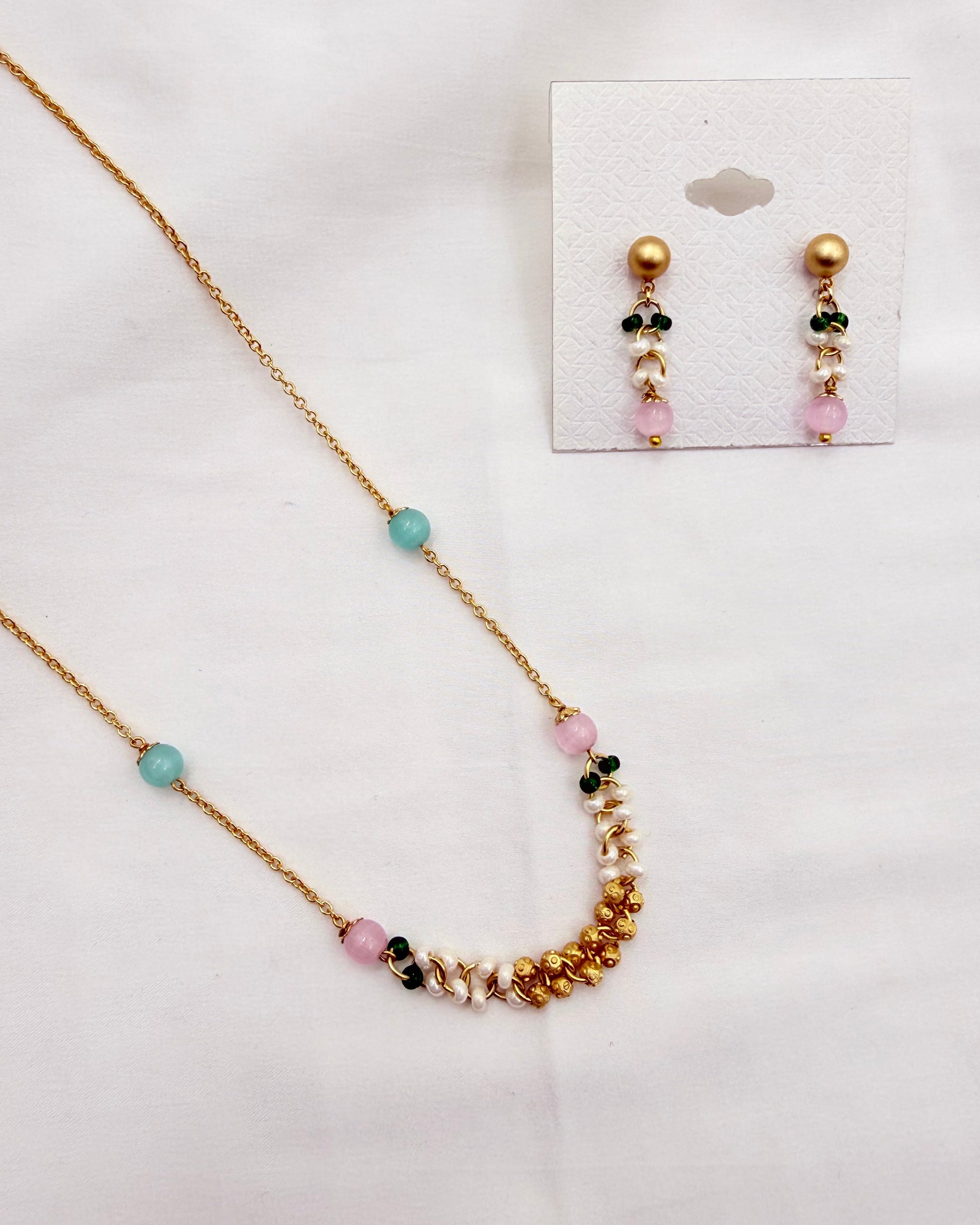 A gold-tone necklace and matching stud earrings set with pastel beads, displayed on a white background. The necklace features a gold chain with a curved section of gold beads, white pearls, and pink, green, and light blue beads.